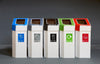 5 trash bins made from cardboard, with different coloured lift off lids in blue, grey, black, green, and red.