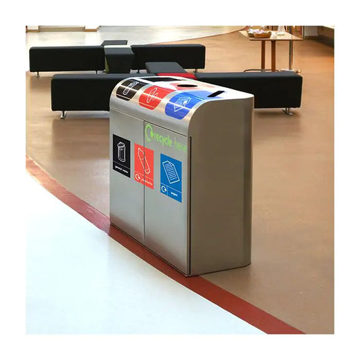 A triple waste trash can with three different graphic stickers attached, situated in the lounge. 
