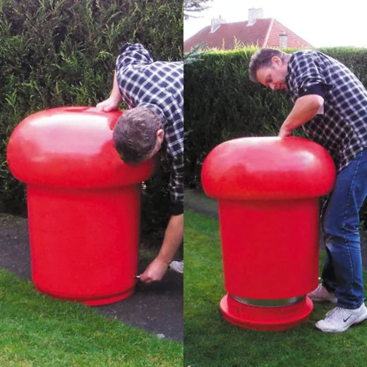 A man setting up the a red mushroom shaped litter bin outdoors. 
