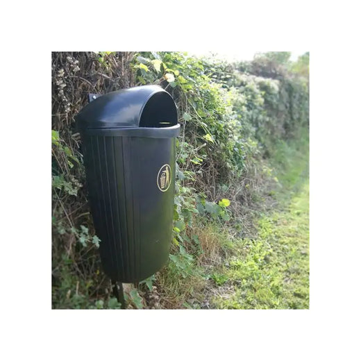 Post mountable litter bin against hedgerow.  Black body with domed li and gold tidyman logo to the front