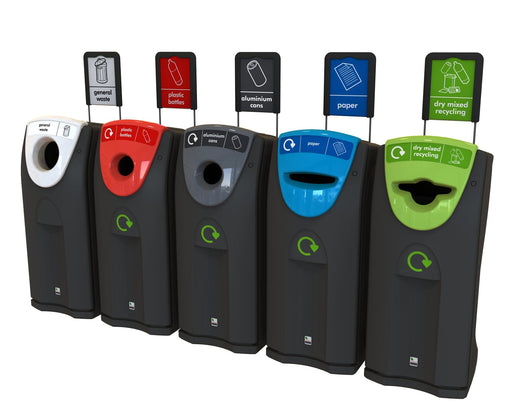 Photo of 5 recycling bins in black base color with different colored apertures and attached recycling labels, arranged from left to right: white, red, grey, blue, and green.