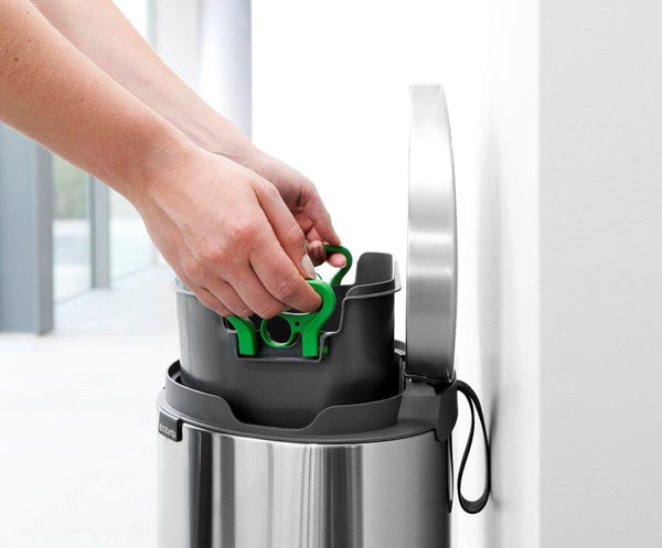 Brabantia flat back bin against a wall with the plastic liner being pulled out
