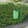 Green mountable litter bin attached to fence.  Tidyman iconography to the front and oval aperture for waste disposal 