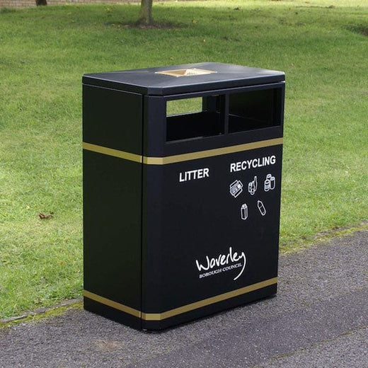 Black dual recycling bin with standard apertures and lid. It has laser cut gold stickers affixed.