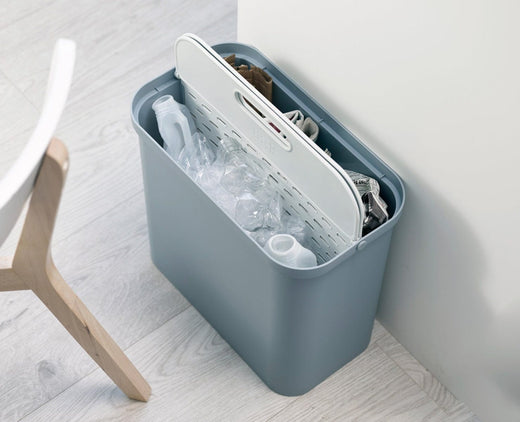 a 2x14 recycling caddy loaded with trash, with papers occupying one side and plastic bottles visible on the opposite side.