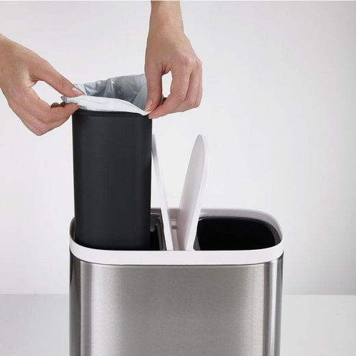 Removal of a plastic-covered inner caddy from one section of the recycling bin.