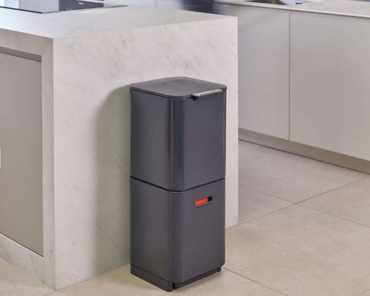 Positioned next to a kitchen counter, a graphite-colored Totem Waste Bin with two stacked compartments 