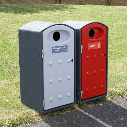 An outdoor recycling bin with domed lid and throw in aperture, placed along roadside. One has red opening door aperture and the other is white. 