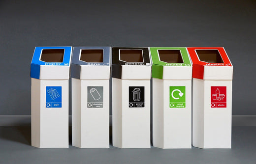 5 white bodied cardboard recycling bins with muti-colored waste streams in blue, grey, black, green and red. 