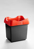 A trash receptacle with a black base features an open top and a lid in striking red.