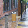 Freestanding circular slatted timber wooden bin located on a pavement